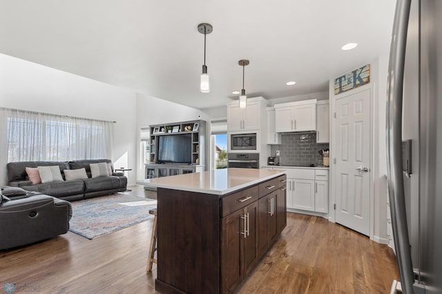 kitchen featuring stainless steel appliances, dark brown cabinets, wood finished floors, and white cabinetry