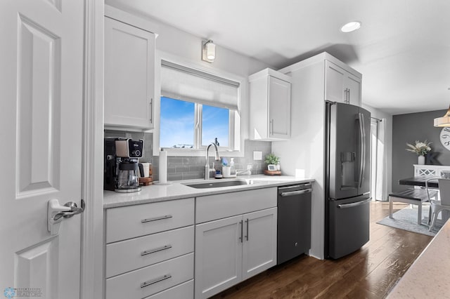 kitchen featuring backsplash, appliances with stainless steel finishes, dark wood-type flooring, white cabinets, and a sink