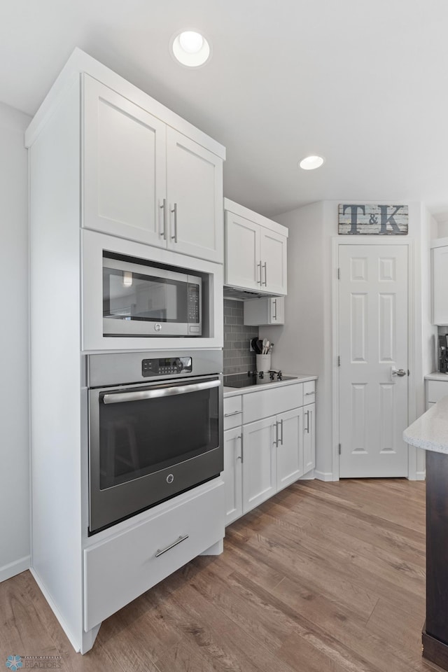 kitchen with light wood-style floors, appliances with stainless steel finishes, and white cabinets