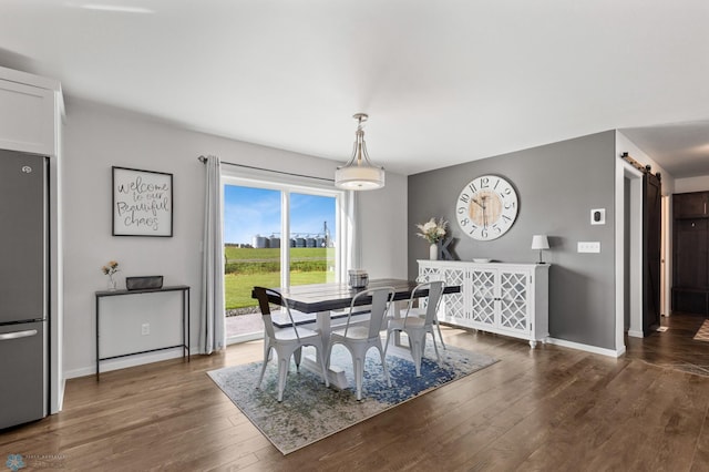 dining room with dark wood-type flooring, baseboards, and a barn door