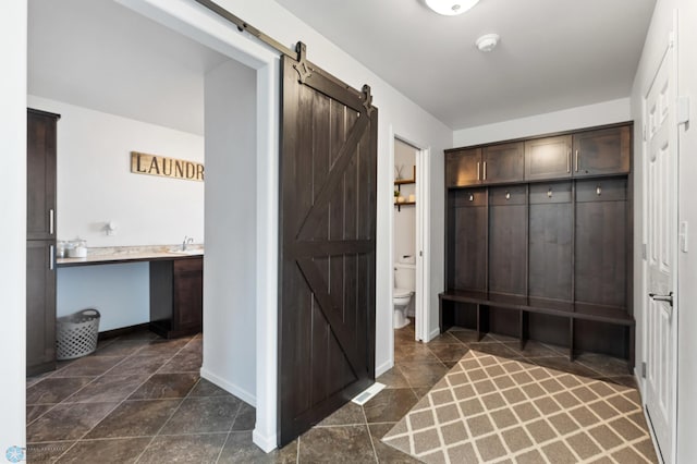 mudroom with a barn door and baseboards