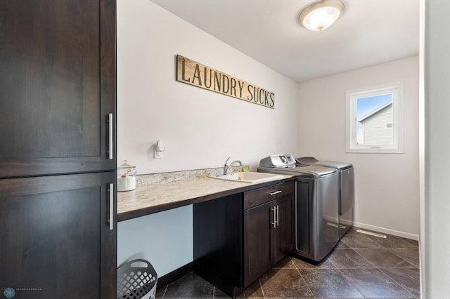 clothes washing area with cabinet space, a sink, washer and clothes dryer, and baseboards