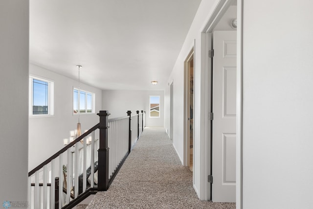 hall with carpet, an upstairs landing, and an inviting chandelier