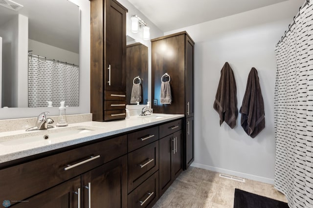 bathroom with double vanity, visible vents, and a sink