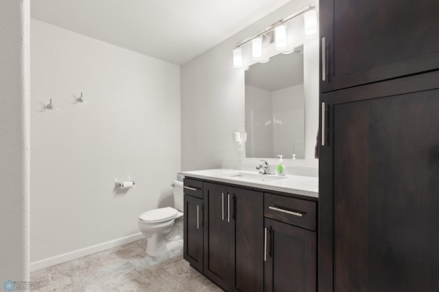 bathroom with vanity, toilet, and baseboards