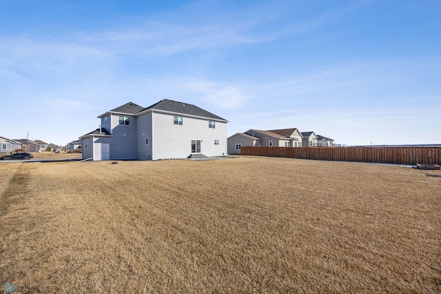 back of property featuring a residential view, fence, and a yard