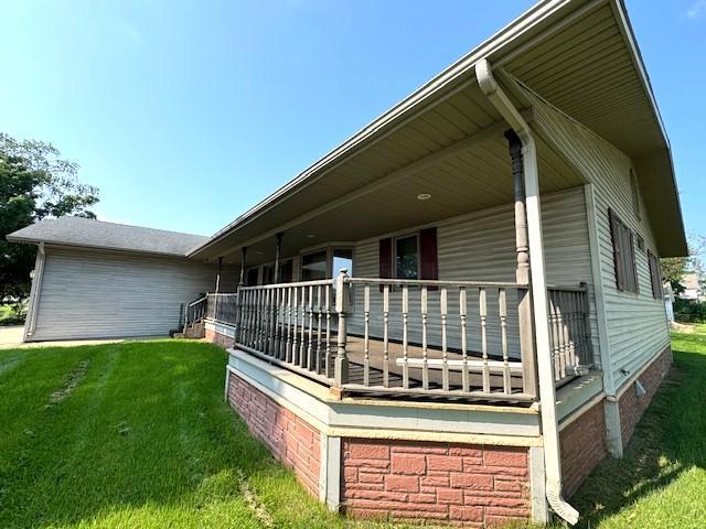 view of side of property featuring covered porch, a lawn, and crawl space