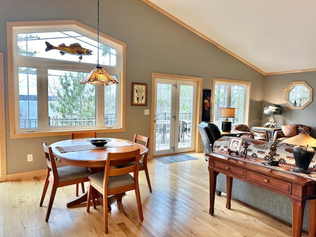 dining room featuring lofted ceiling, light wood-type flooring, baseboards, and crown molding