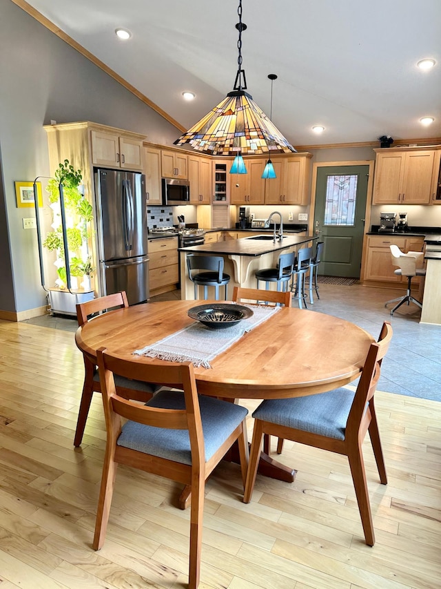 dining space with lofted ceiling, light wood finished floors, ornamental molding, and recessed lighting