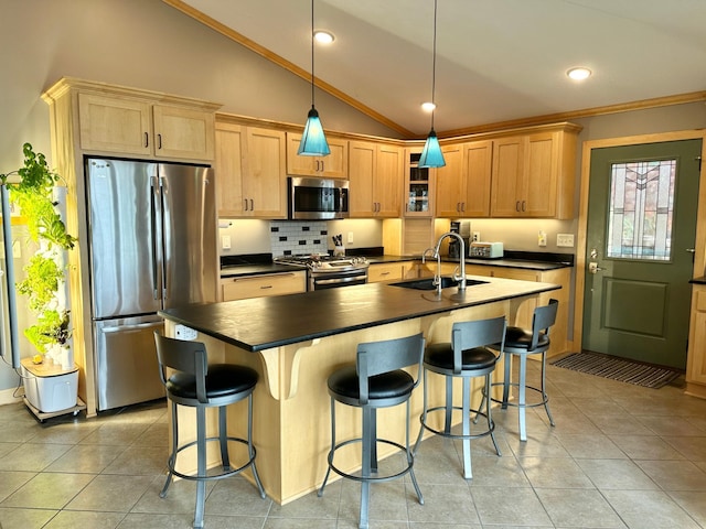 kitchen featuring light tile patterned floors, dark countertops, vaulted ceiling, stainless steel appliances, and a sink