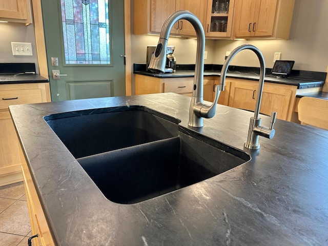 room details with dark countertops, a sink, and glass insert cabinets