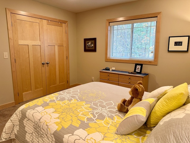 carpeted bedroom with a closet and baseboards