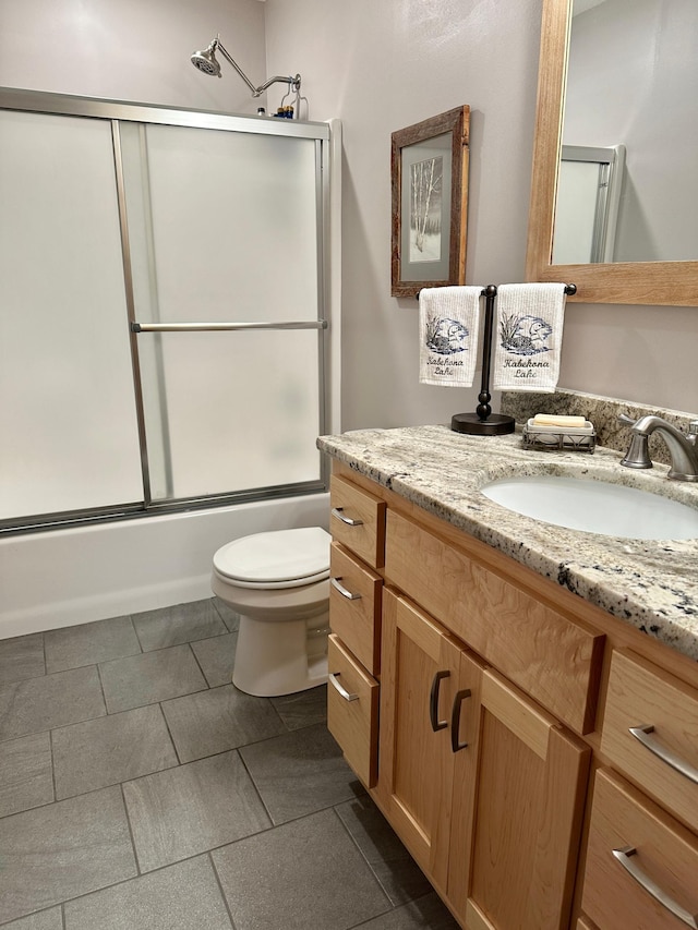 full bathroom featuring toilet, combined bath / shower with glass door, and vanity