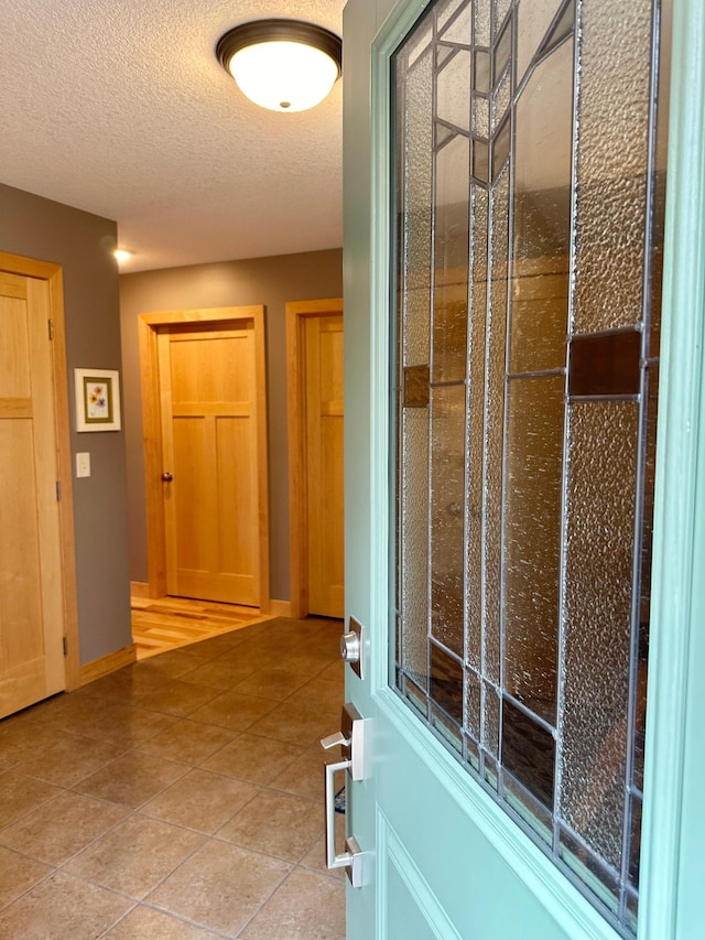 interior space featuring tile patterned flooring, a textured ceiling, and baseboards