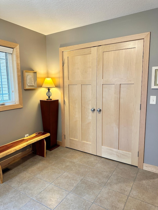 interior space with a textured ceiling and baseboards