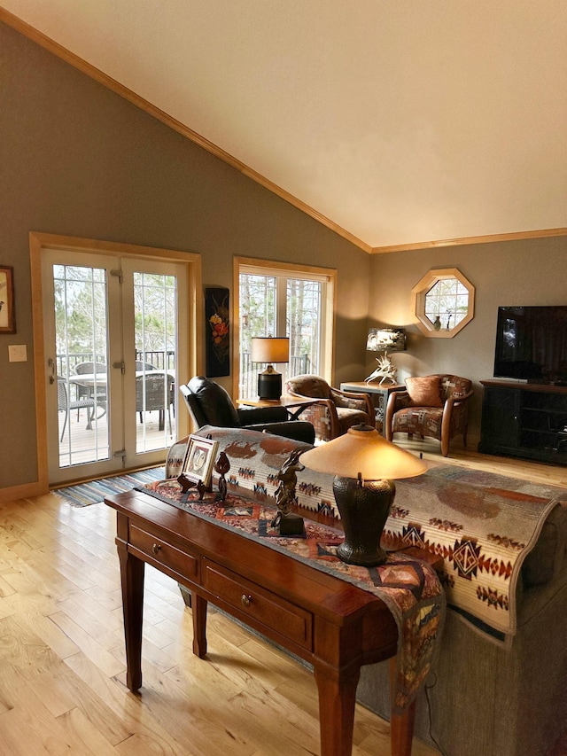 interior space featuring lofted ceiling, light wood-style flooring, ornamental molding, and french doors