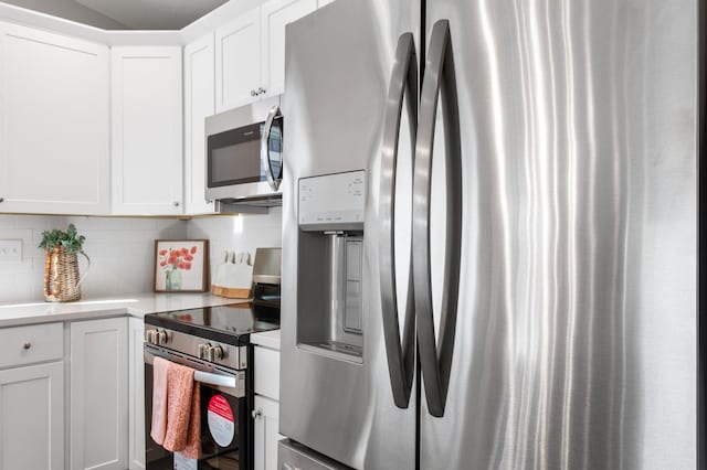 kitchen featuring tasteful backsplash, appliances with stainless steel finishes, white cabinetry, and light countertops