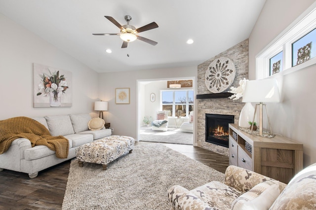 living area with recessed lighting, a stone fireplace, ceiling fan, dark wood-style flooring, and vaulted ceiling