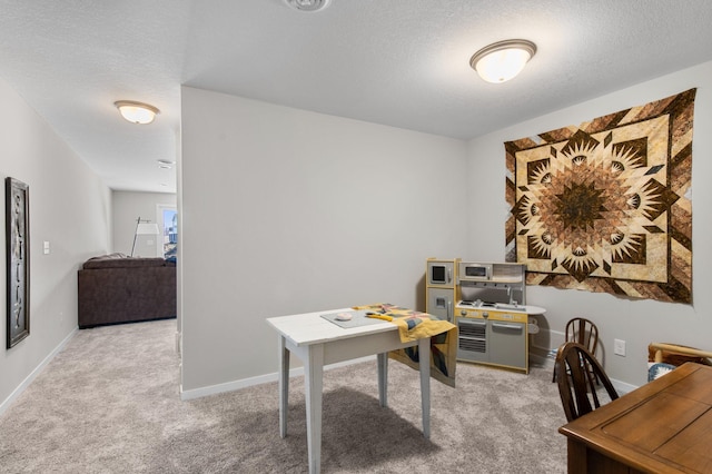 home office with a textured ceiling, baseboards, and light carpet