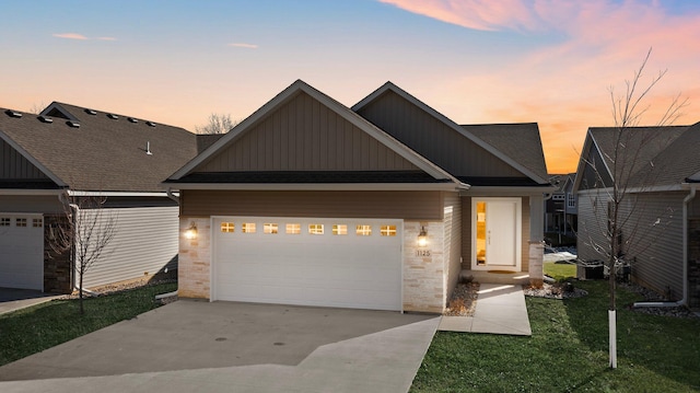 view of front of house featuring stone siding, an attached garage, board and batten siding, and driveway