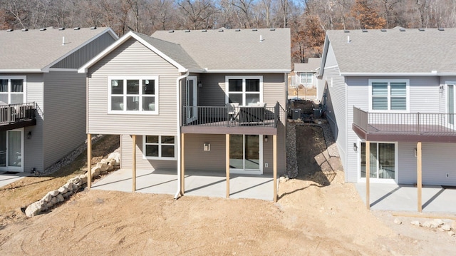 rear view of house with a patio and roof with shingles