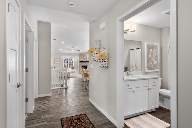 1125 Hewitt Blvd, Red Wing, MN 55066 - hallway featuring baseboards, dark wood-style flooring, an upstairs landing, recessed lighting, and a sink