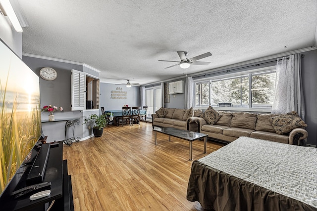 living room featuring ornamental molding, light wood-style flooring, and a textured ceiling