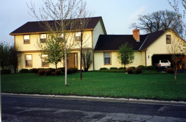 view of front of property with a garage, a chimney, and a front lawn