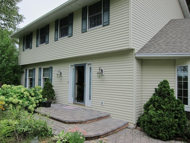 back of property with a patio area and roof with shingles