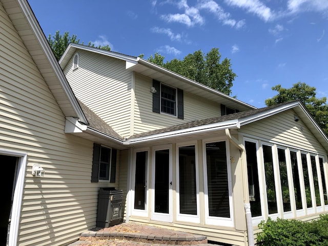 view of side of home featuring roof with shingles and a sunroom