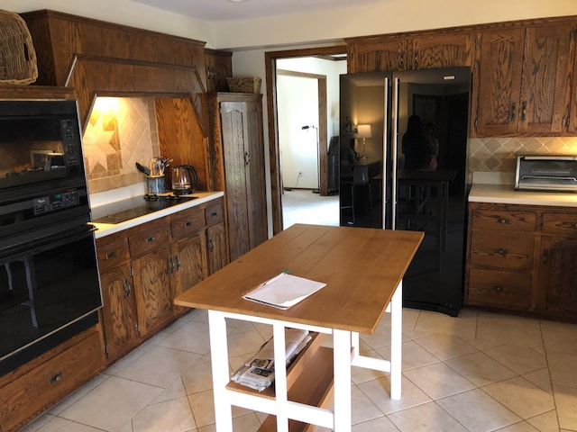 kitchen featuring light tile patterned floors, a toaster, black appliances, light countertops, and tasteful backsplash