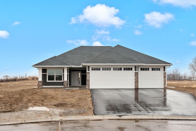 view of front of home featuring driveway, stone siding, an attached garage, and roof with shingles