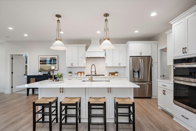 kitchen featuring custom exhaust hood, a breakfast bar, appliances with stainless steel finishes, and light countertops