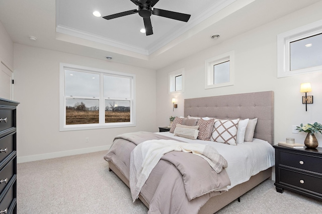 bedroom featuring light colored carpet, baseboards, multiple windows, a tray ceiling, and crown molding