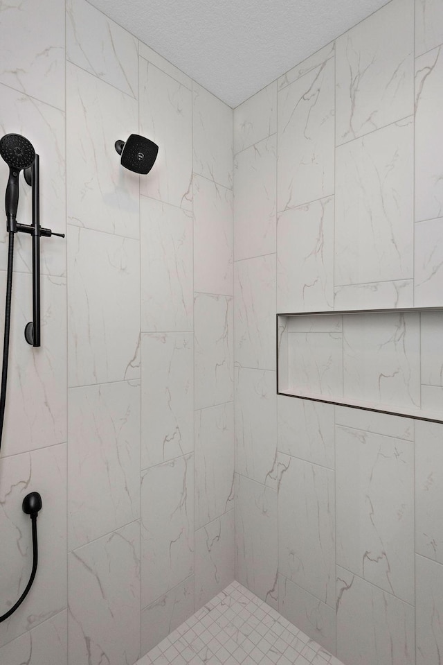 full bathroom featuring a tile shower and a textured ceiling