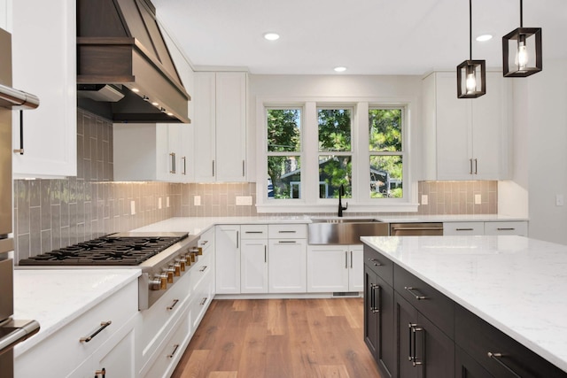 kitchen with custom range hood, white cabinets, a sink, and stainless steel gas stovetop