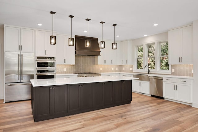 kitchen with stainless steel appliances, white cabinetry, light countertops, a center island, and custom range hood