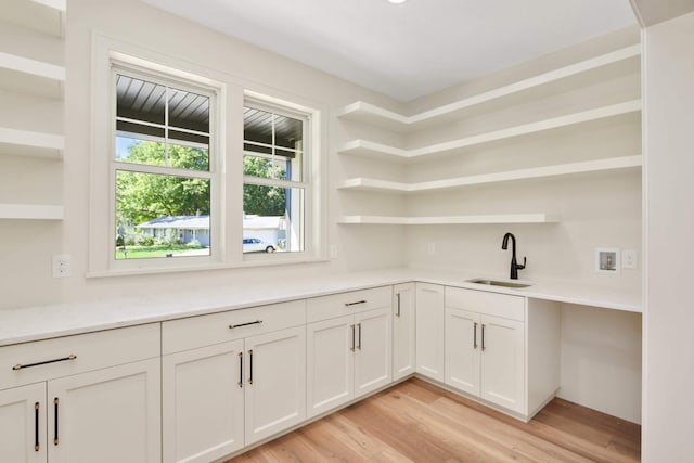 interior space with open shelves, light wood finished floors, a sink, and light countertops