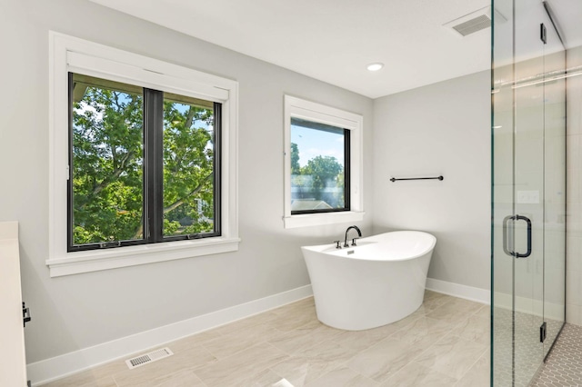 full bathroom with a freestanding tub, a shower stall, visible vents, and baseboards