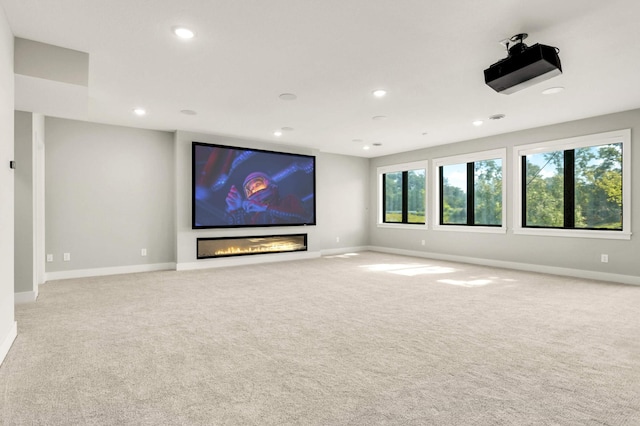 home theater with recessed lighting, light carpet, a glass covered fireplace, and baseboards