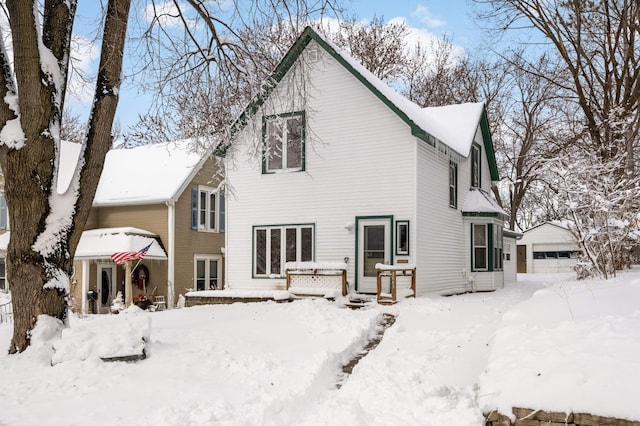 snow covered house featuring a garage and an outdoor structure