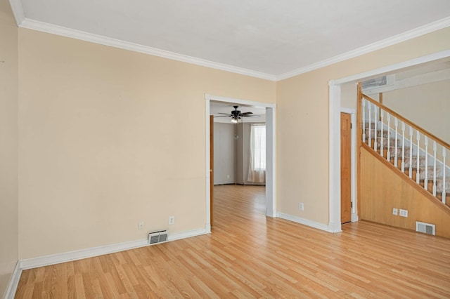 spare room with light wood finished floors, stairway, visible vents, and crown molding