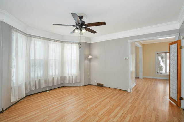 spare room featuring baseboards, visible vents, a ceiling fan, ornamental molding, and wood finished floors