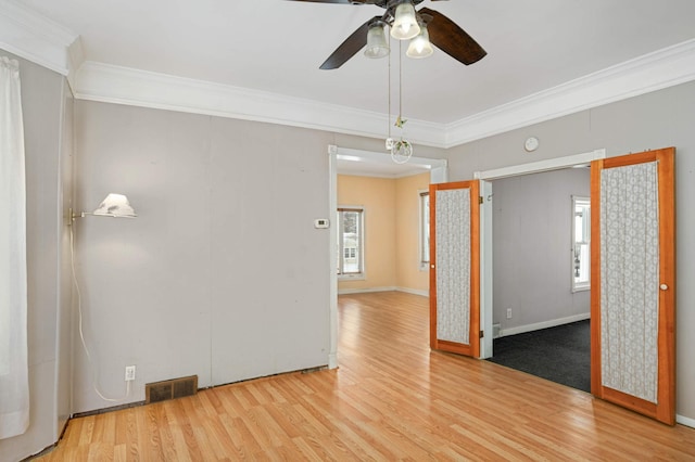 unfurnished room featuring crown molding, visible vents, ceiling fan, wood finished floors, and baseboards