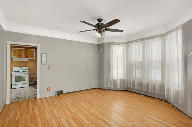 empty room featuring wood finished floors, visible vents, and crown molding