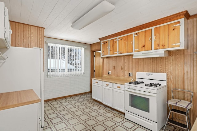 kitchen with white appliances, wooden walls, light floors, light countertops, and under cabinet range hood