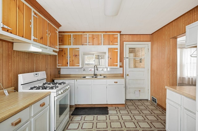 kitchen with under cabinet range hood, white range with gas stovetop, light countertops, and a sink