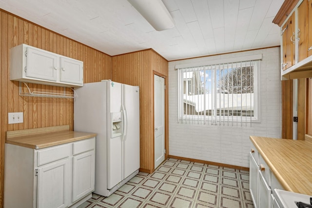 kitchen with light floors, white refrigerator with ice dispenser, light countertops, and white cabinets