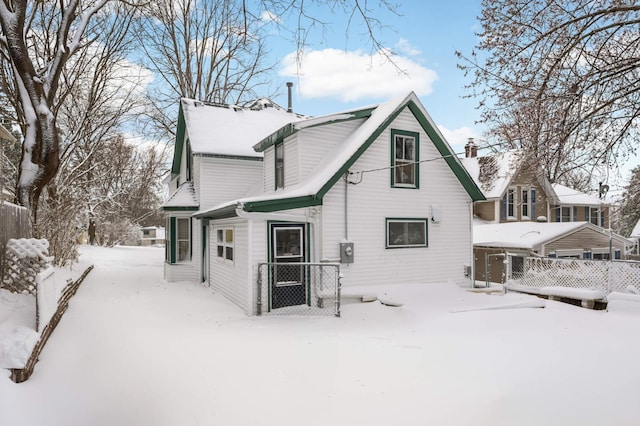 snow covered rear of property featuring fence