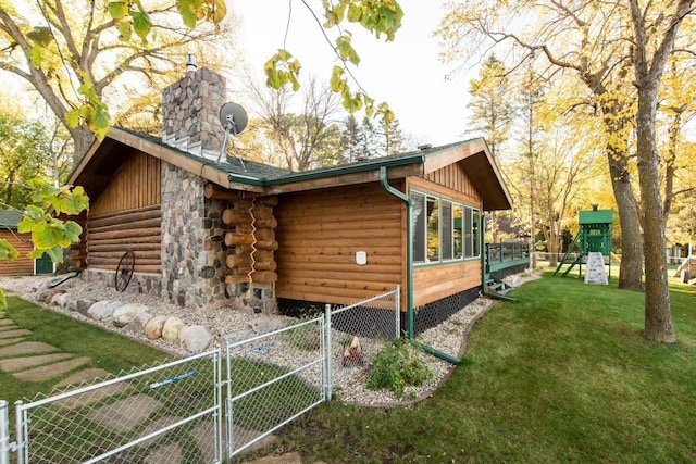 view of side of home with a yard, a chimney, a gate, fence, and log exterior